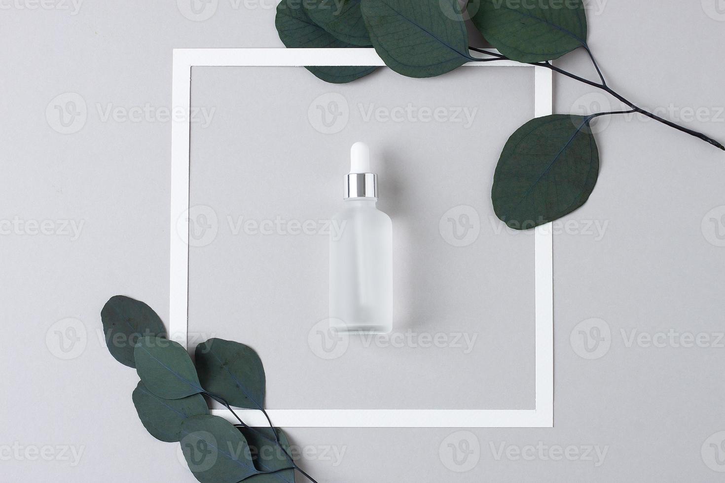 White frame with cosmetic bottle on grey background. Flat lay. photo