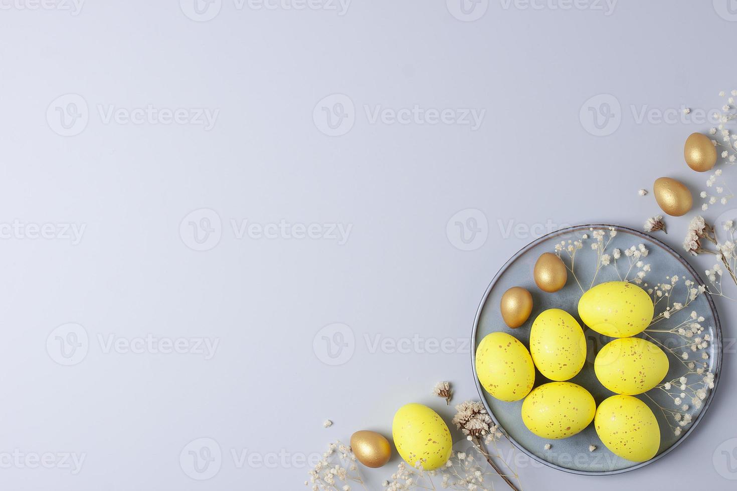 Grey plate with easter yellow eggs and flowers on grey background. Flat lay, copy space. photo