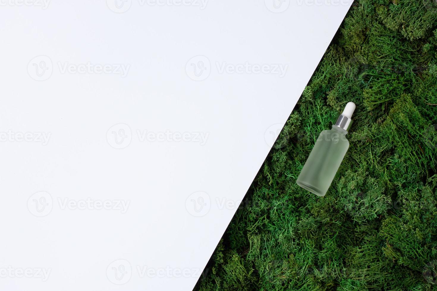 Cosmetic bottle with green moss natural background on white. Flat lay, copy space photo