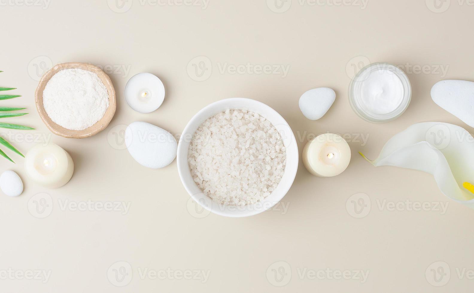 Spa composition with skin care products, stones, candles and palm leaves on pastel beige. Flat lay, copy space photo
