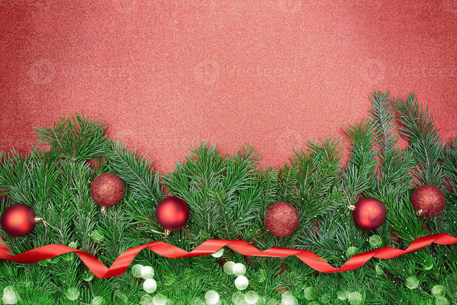 Fir branches with red shiny and matte balls, ribbon with bokeh on sparkling background. Christmas, New Year. Copy space photo