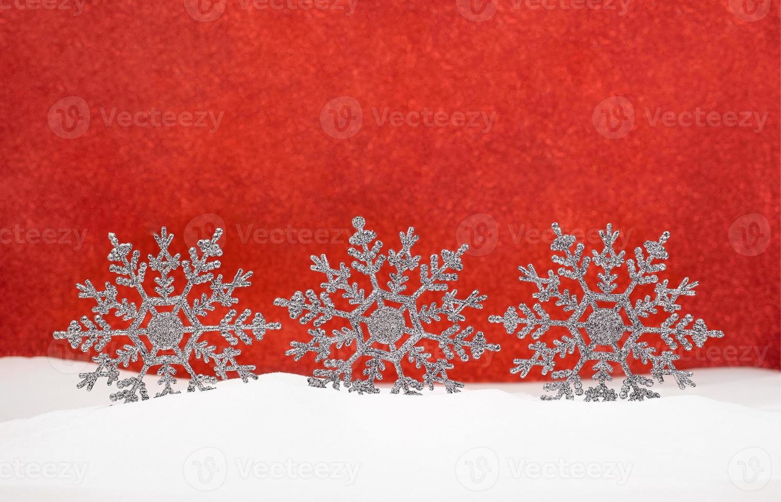 Shiny snowflakes on snow with red blurred background. Christmas, New Year. Copy space photo