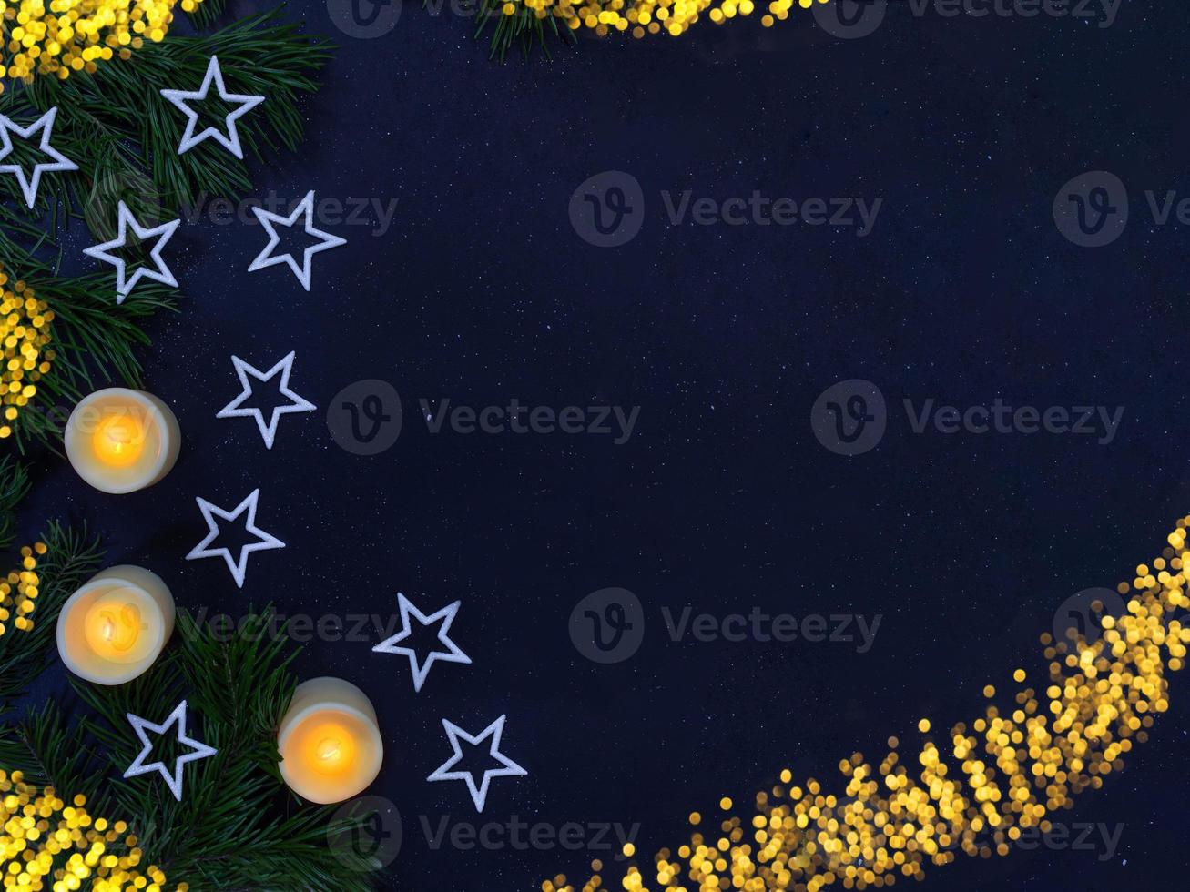 White shiny stars, burning candles, fir branches on black background with defocused lights. Christmas, New Year, holiday. Copy space photo