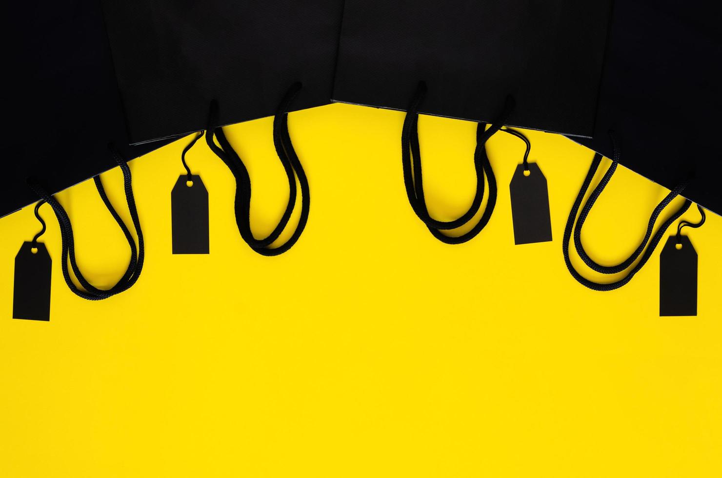 Black price tags with shopping paper bags on yellow background for Black Friday shopping sale concept. photo