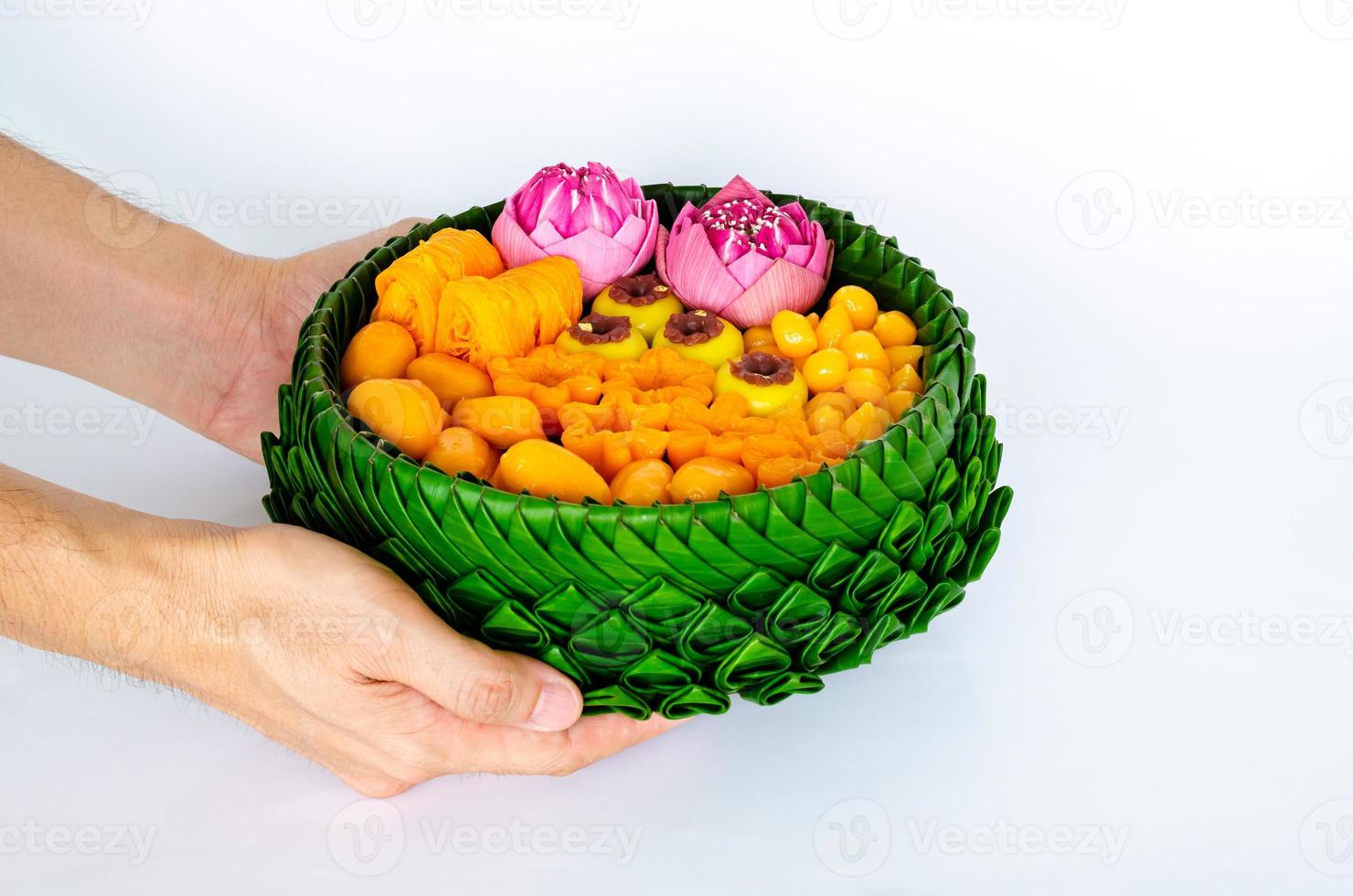 Hand holding partial focus of Thai wedding desserts on banana leaves plate or krathong for thai traditional ceremony on white background. photo