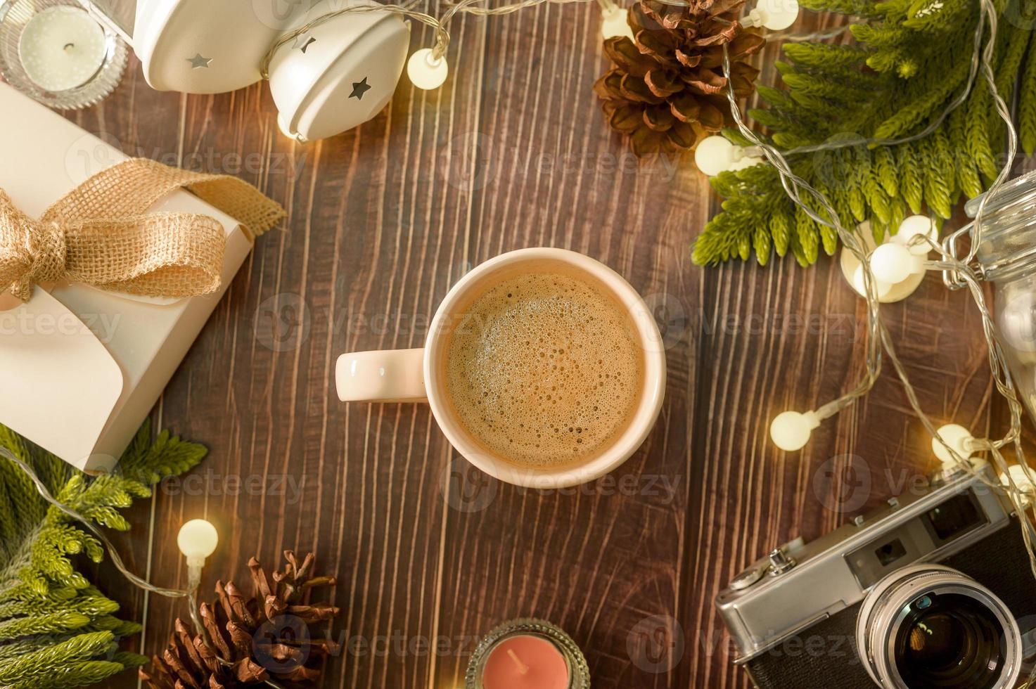taza de café sobre luces de navidad bokeh en casa en decoraciones de mesa de madera. decoración de vacaciones de invierno, concepto de decoración de navidad y año nuevo foto