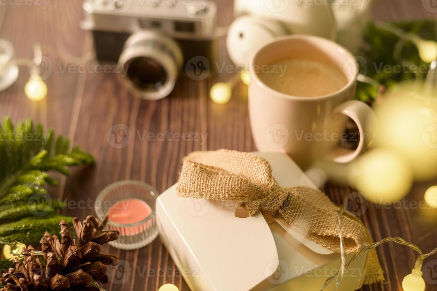 taza de café sobre luces de navidad bokeh en casa en decoraciones de mesa de madera. decoración de vacaciones de invierno, concepto de decoración de navidad y año nuevo foto