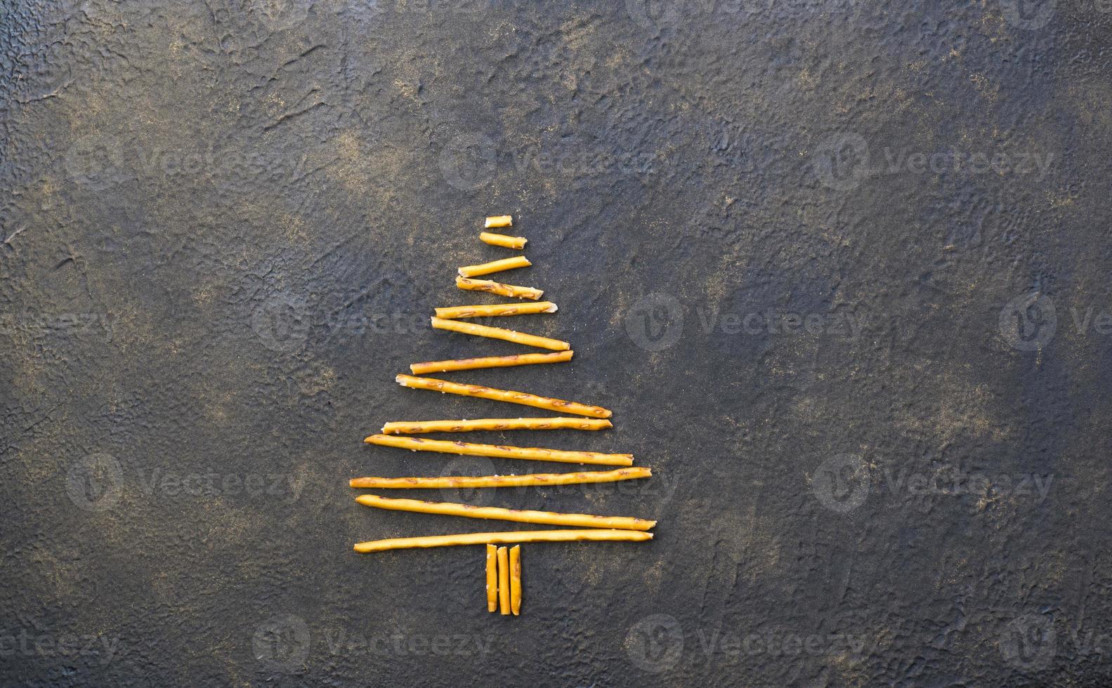 árbol de navidad hecho de galletas de pajitas de pepero, sobre fondo de textura negra. vista desde arriba. foto