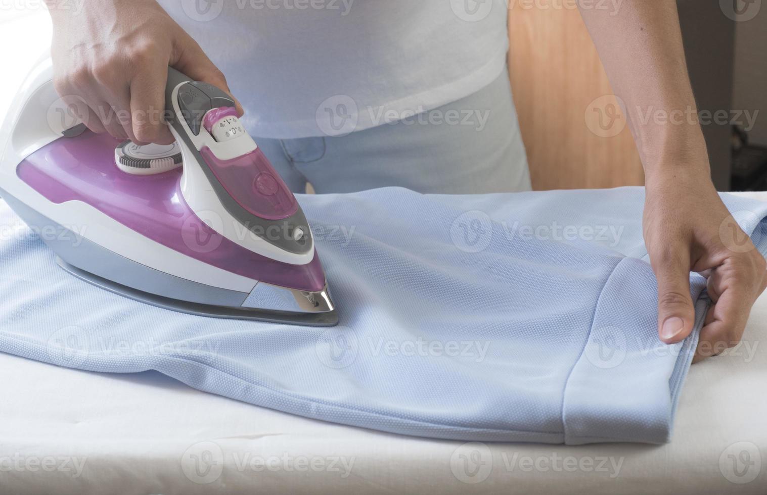 closeup hand of woman ironing clothes blue skirt on ironing board. photo