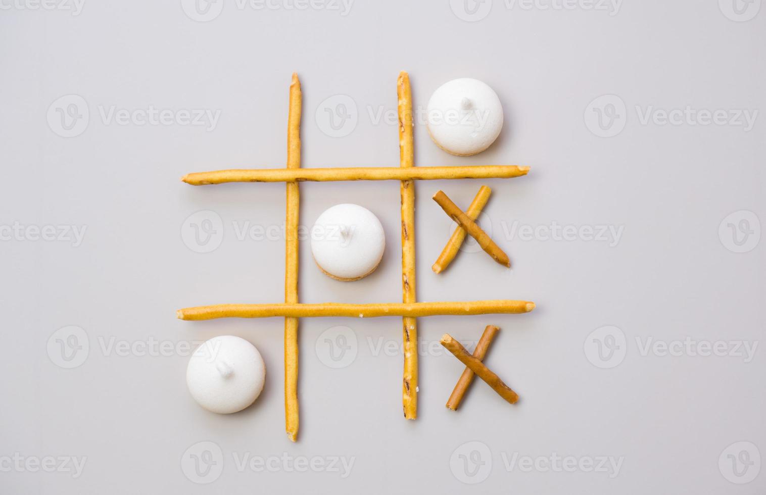 tic-tac-toe from crackers and sticks on a gray background. Food concept. Edible snacks dry sticks with salt and cookies on a white plate. Straws, sticks for crackers. photo