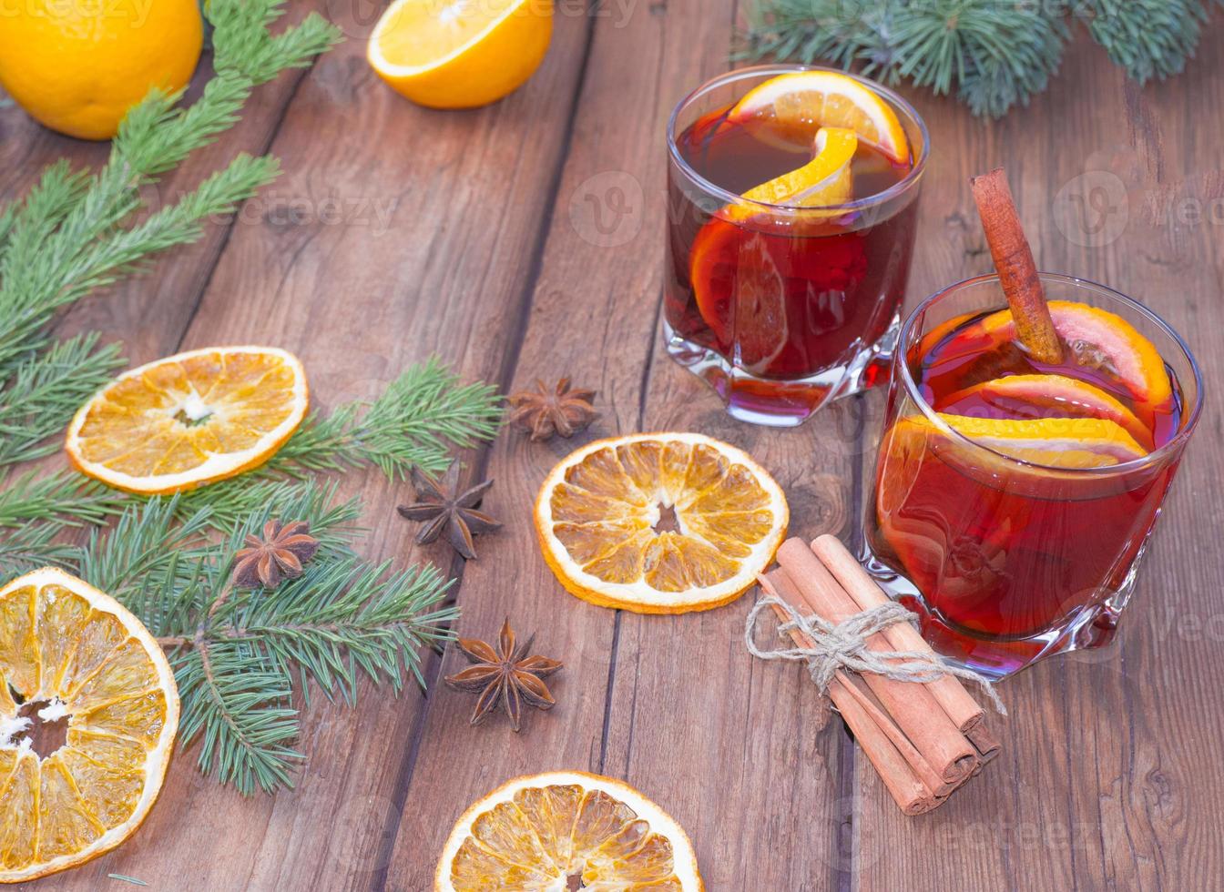 Christmas mulled wine on a wooden background with spices and spruce branches and dried orange. photo