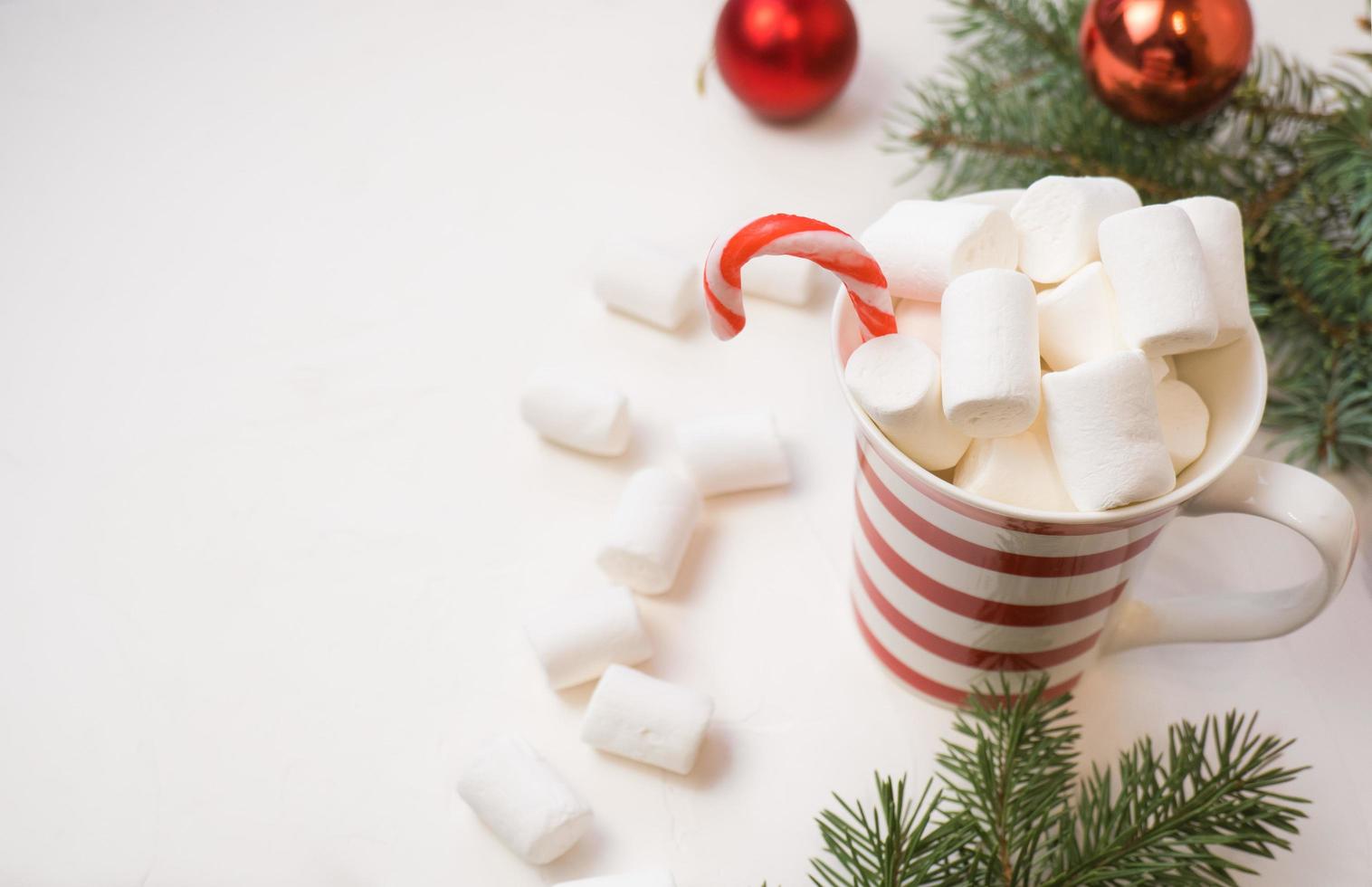 Traditional hot chocolate with marshmallows and lollipops on a white textured background. Christmas drink theme. photo