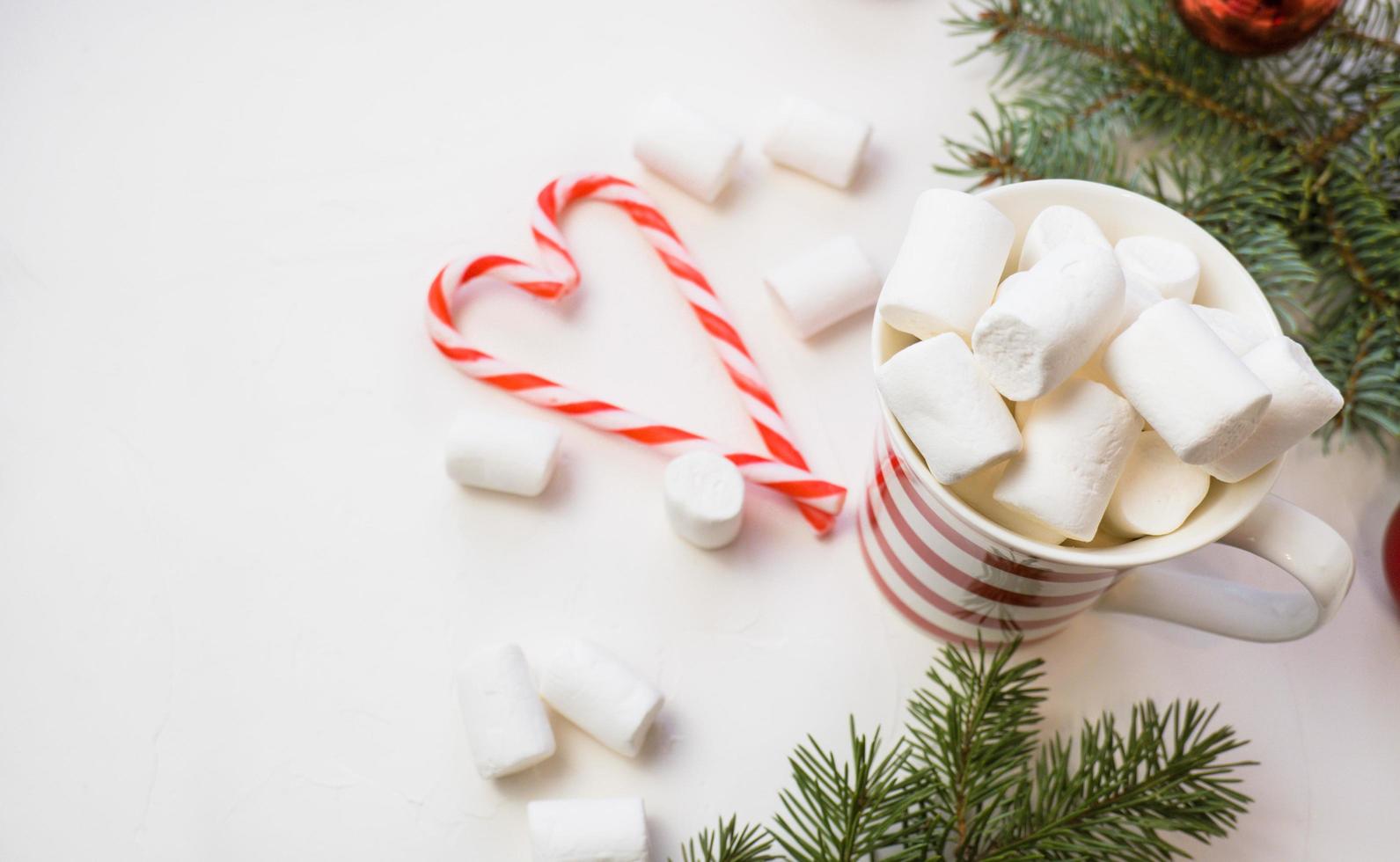 Traditional hot chocolate with marshmallows and lollipops on a white textured background. Christmas drink theme. photo