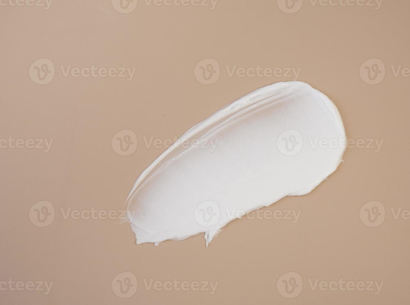 White cosmetic cream smears on a dark beige background. Facial lotion smear serum. The texture of the cosmetic product photo