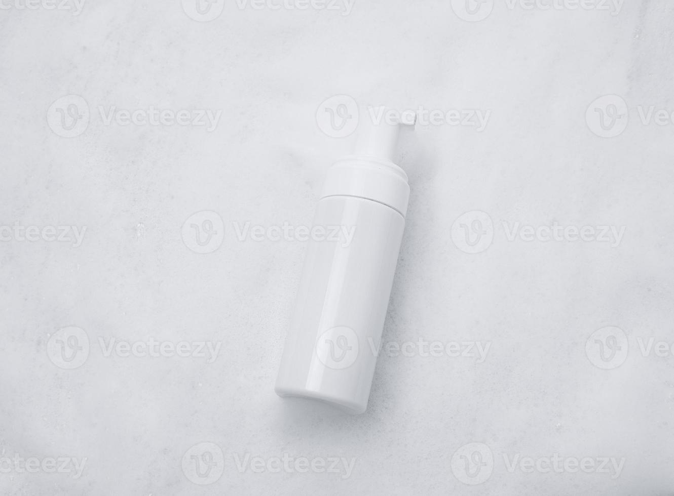 White plastic tube mockup with moisturizer cream, shampoo or facial cleanser and gentle soap foam with bubbles on marble background, top view. Treatment spa beauty skincare cosmetic product photo