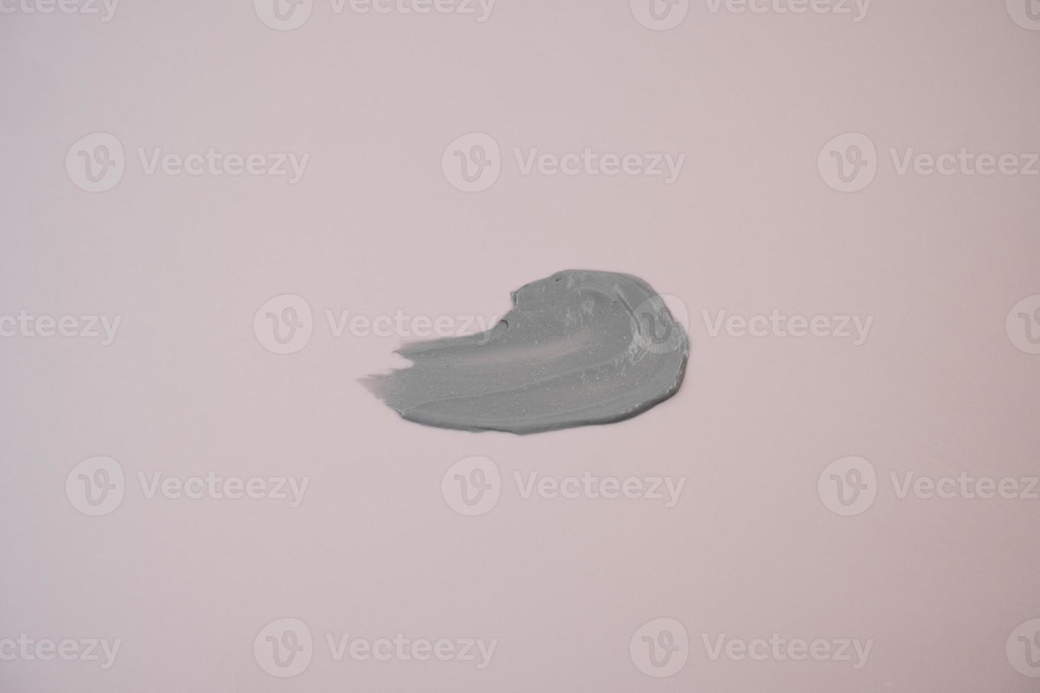 Cosmetic mud smear of facial mask, scrub with black clay on purple background. photo