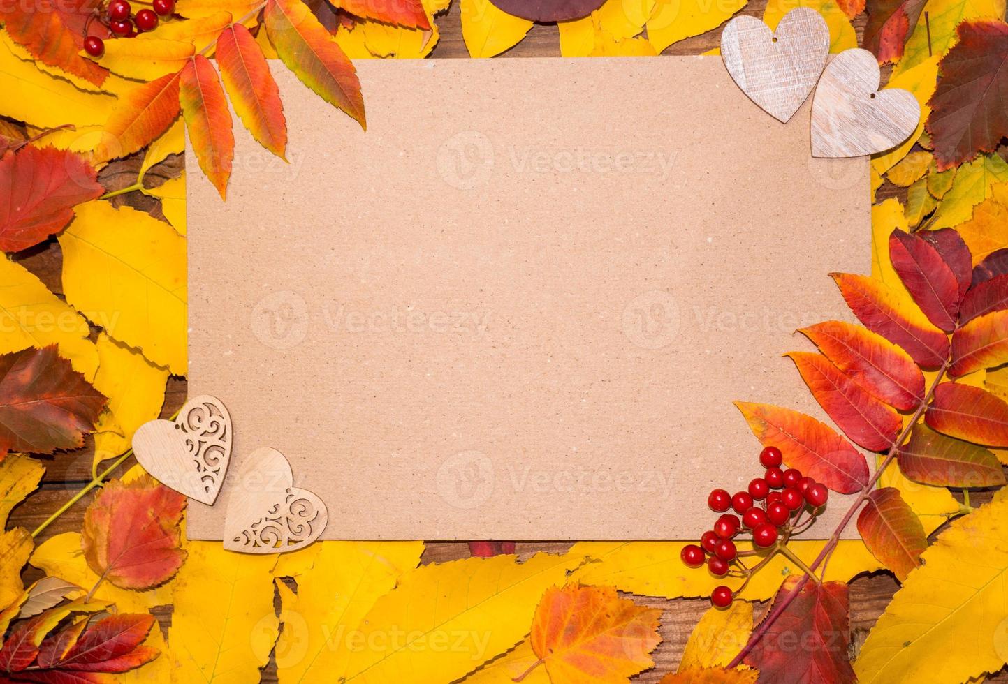 Hello October. Autumn composition, top view of autumn bright colorful leaves with a sheet of paper and wooden two hearts. space for text photo