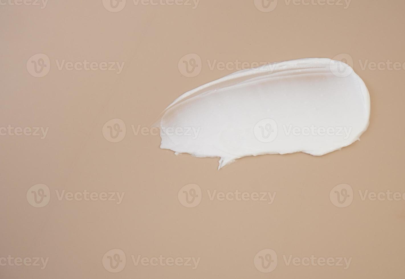 White cosmetic cream smears on a dark beige background. Facial lotion smear serum. The texture of the cosmetic product. photo