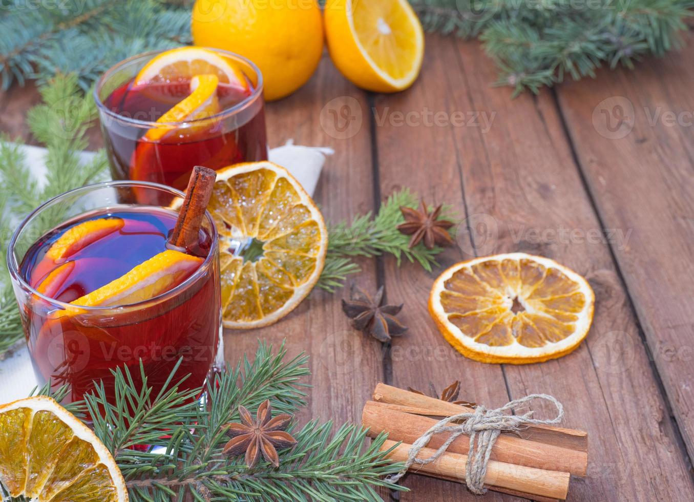 Christmas mulled wine on a wooden background with spices and spruce branches and dried orange. photo