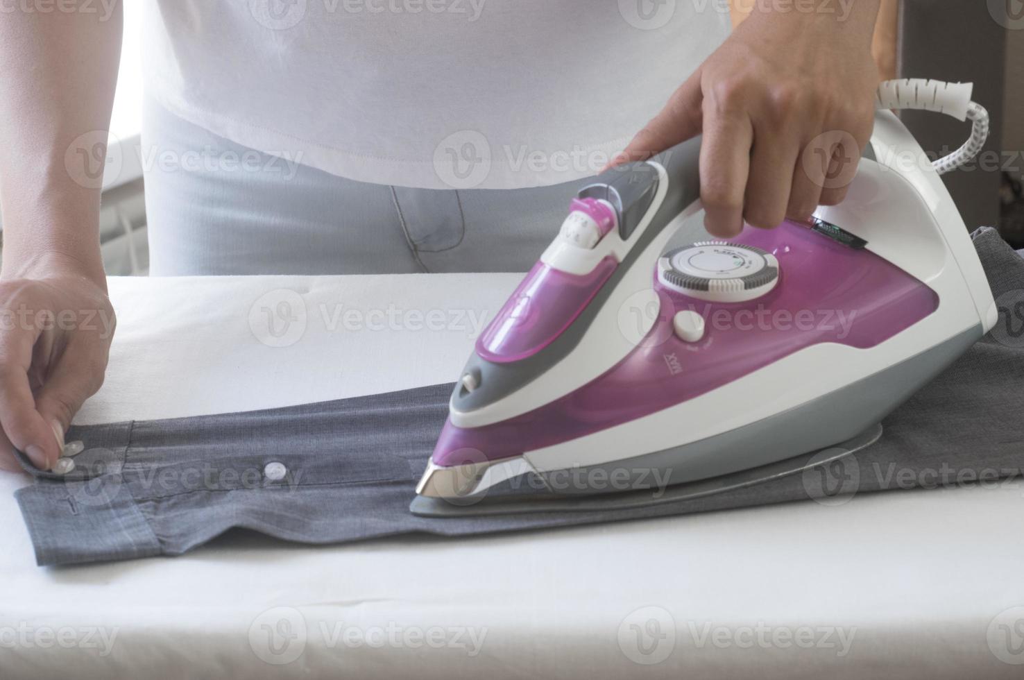 closeup hand of woman ironing clothes blue skirt on ironing board. photo