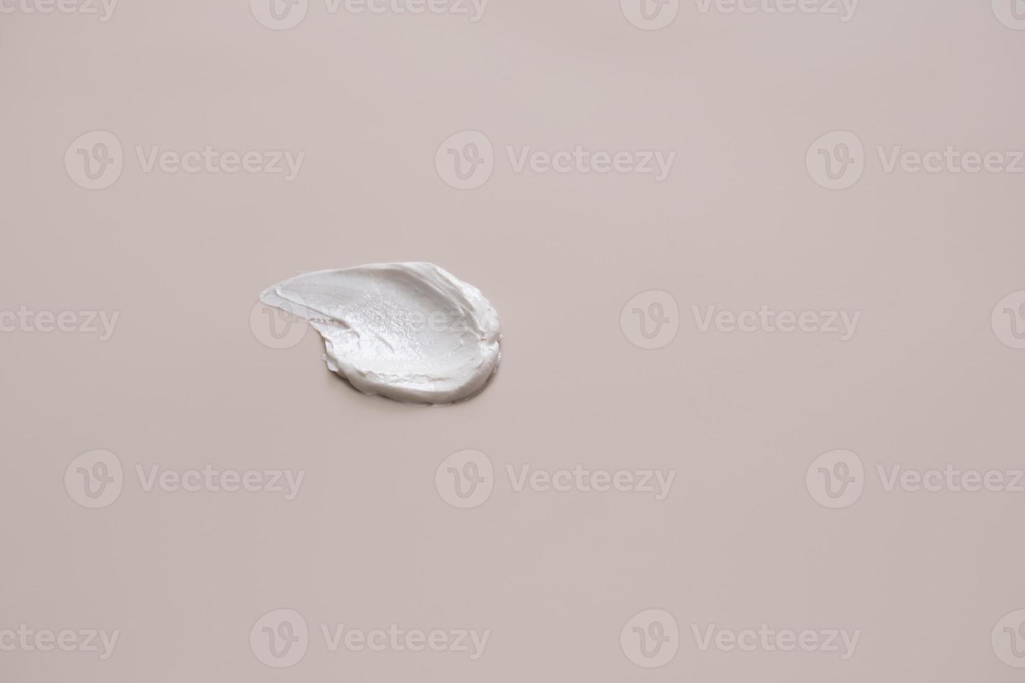 The texture of white delicate cream on a beige background. photo