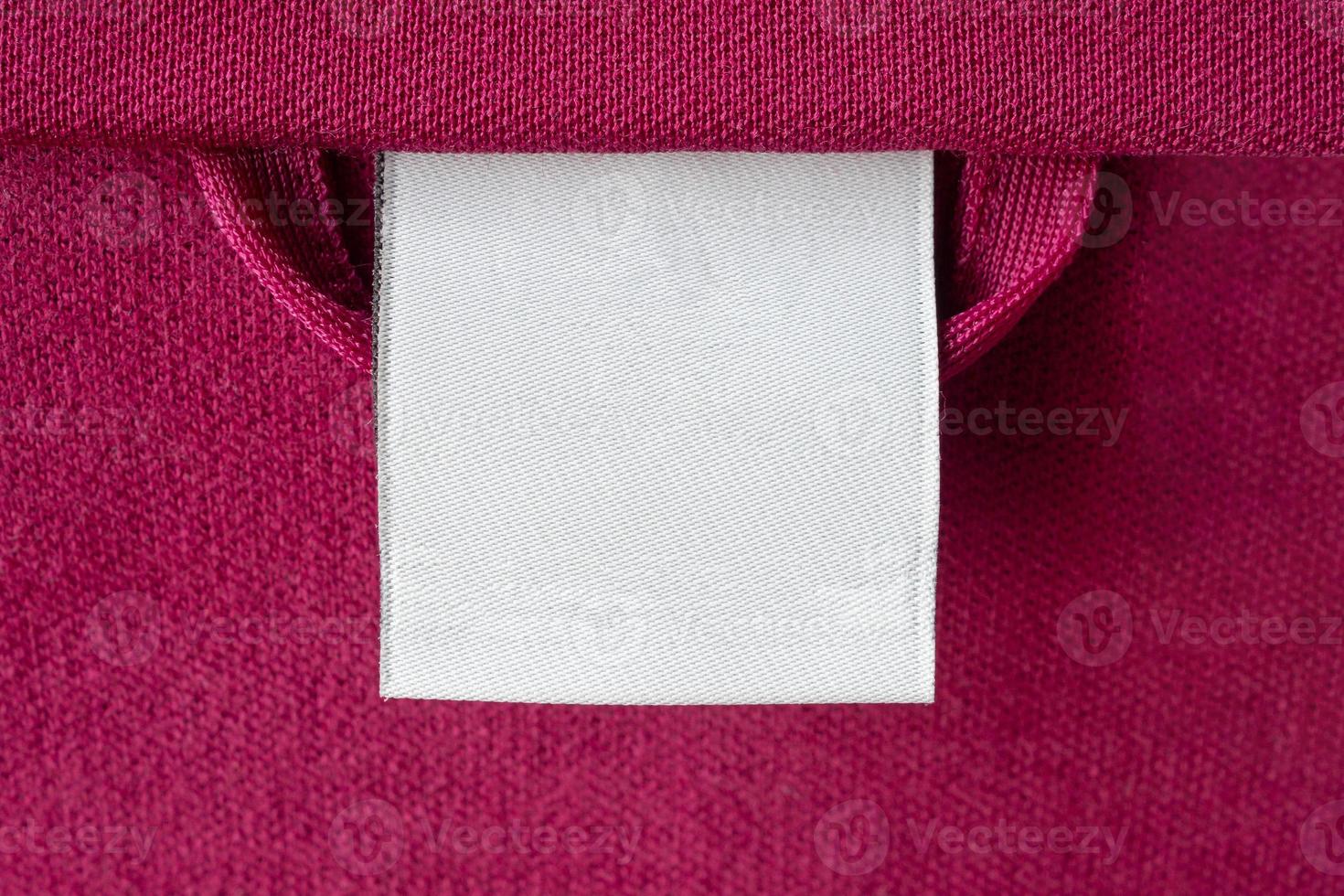 Blank white laundry care clothes label on red fabric texture background photo