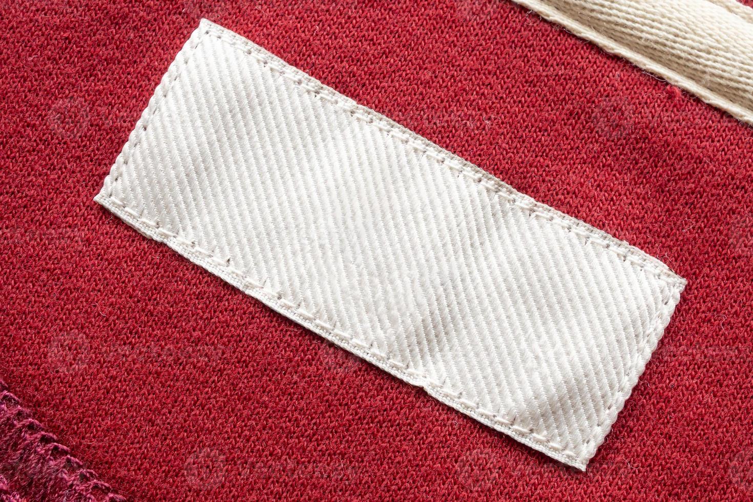 Blank white laundry care clothes label on red fabric texture background photo