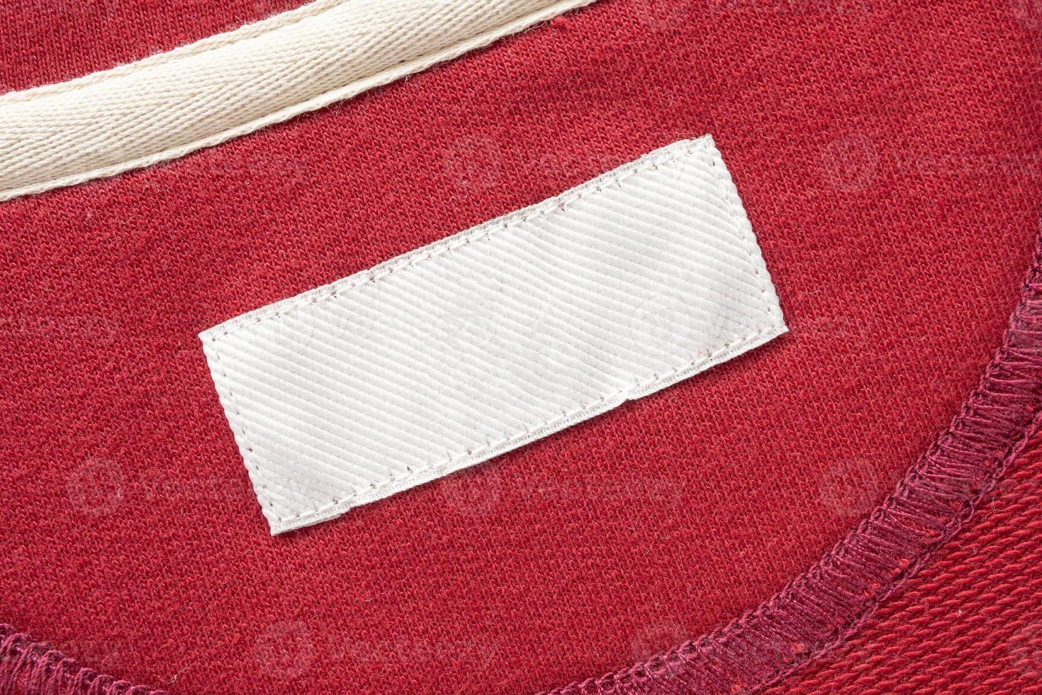 Blank white laundry care clothes label on red fabric texture background photo