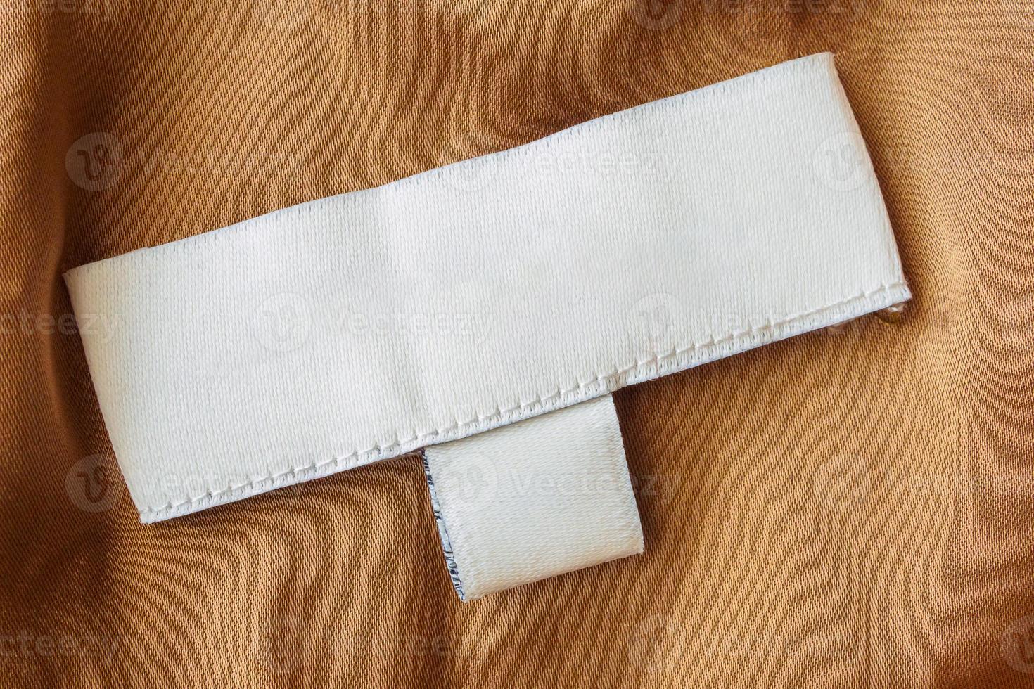 Blank white laundry care clothes label on brown fabric texture background photo