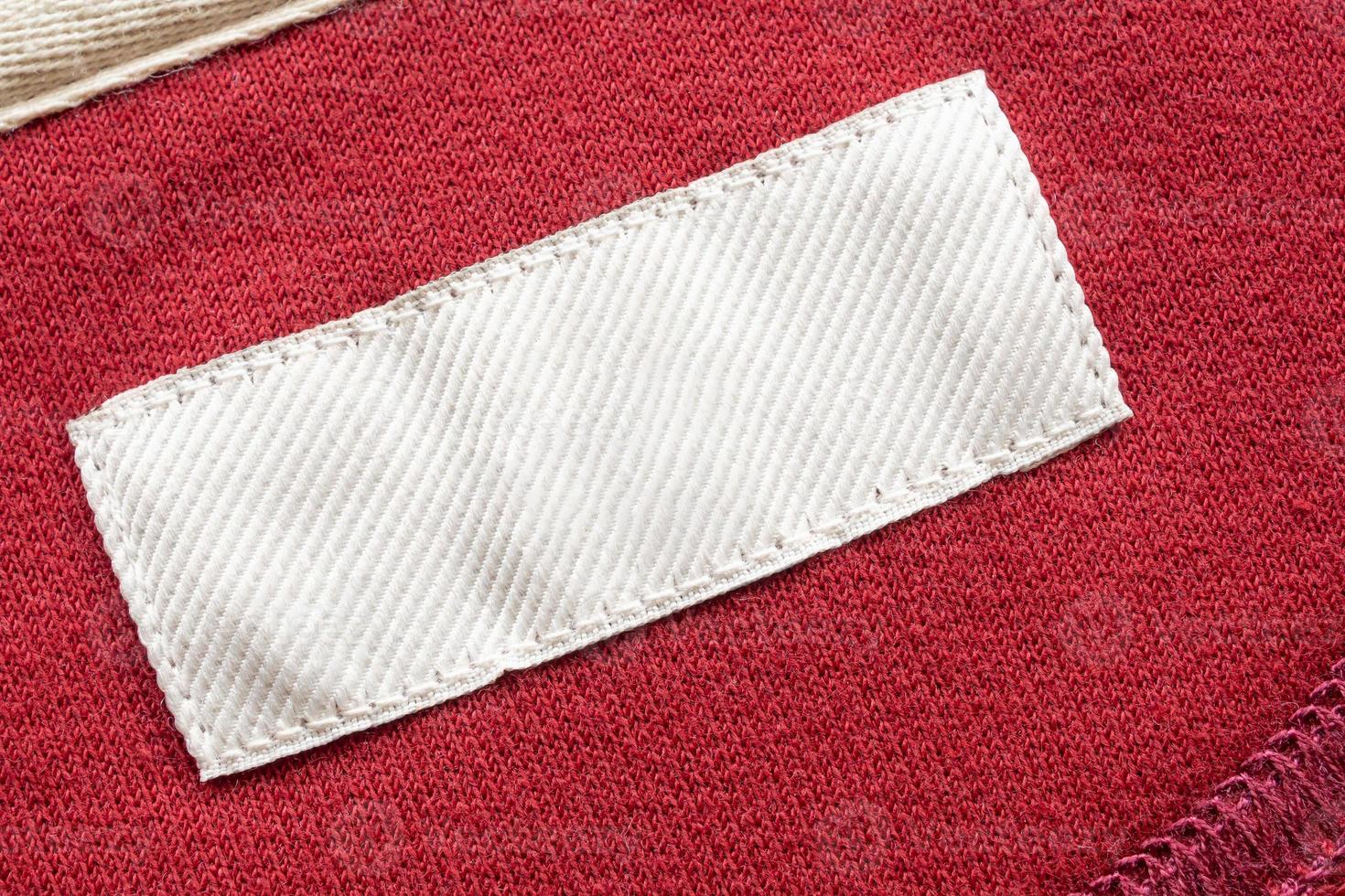 Blank white laundry care clothes label on red fabric texture background photo