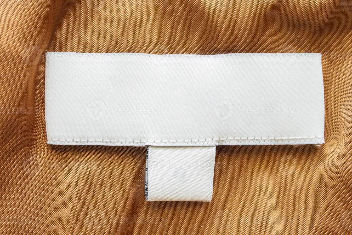 Blank white laundry care clothes label on brown fabric texture background photo