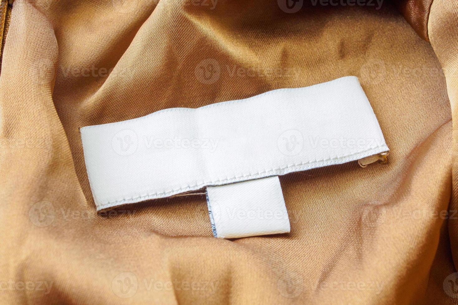 Blank white laundry care clothes label on brown fabric texture background photo