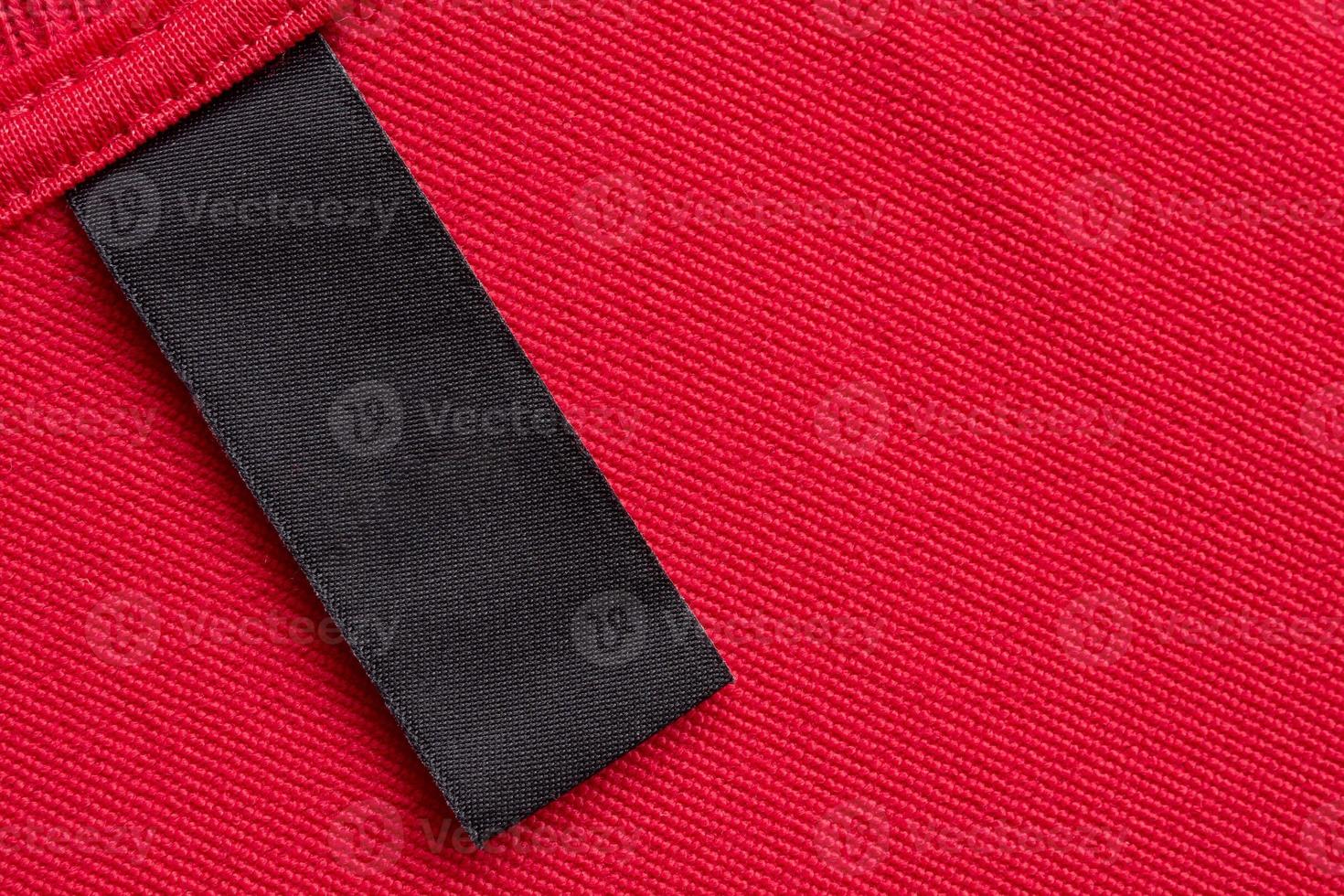 Blank black laundry care clothes label on red fabric texture background photo