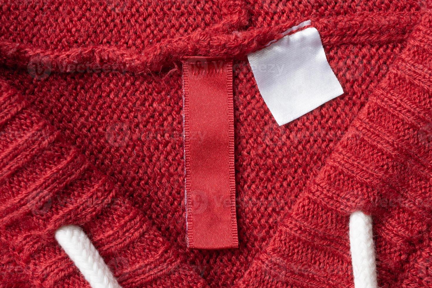 Blank laundry care clothes label on red knitted fabric texture background photo