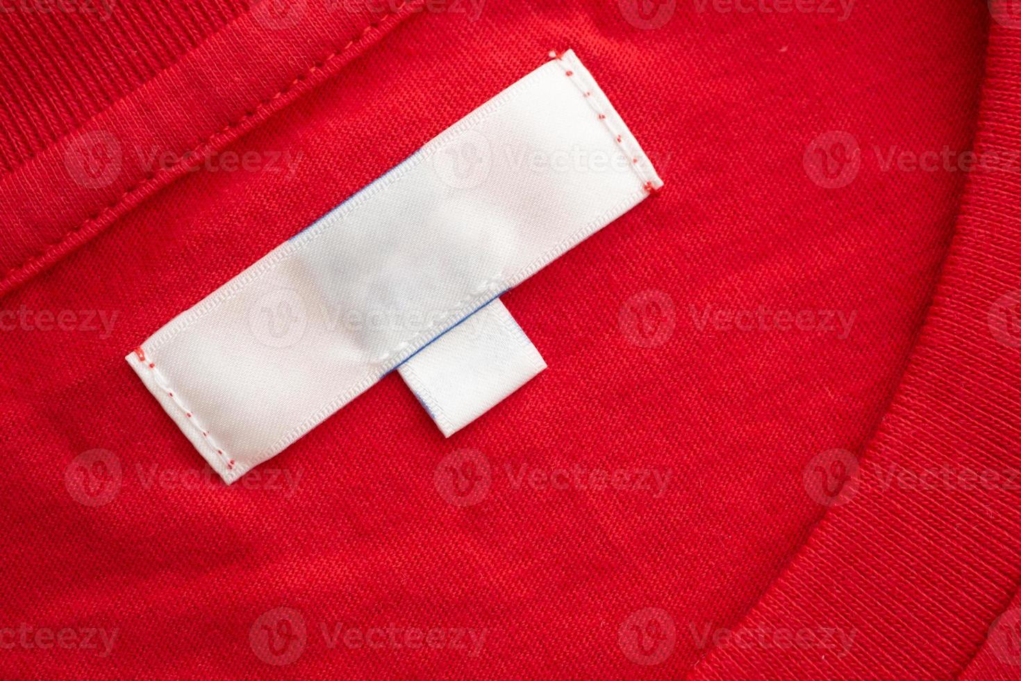White blank clothing tag label on new red cotton shirt fabric texture background photo