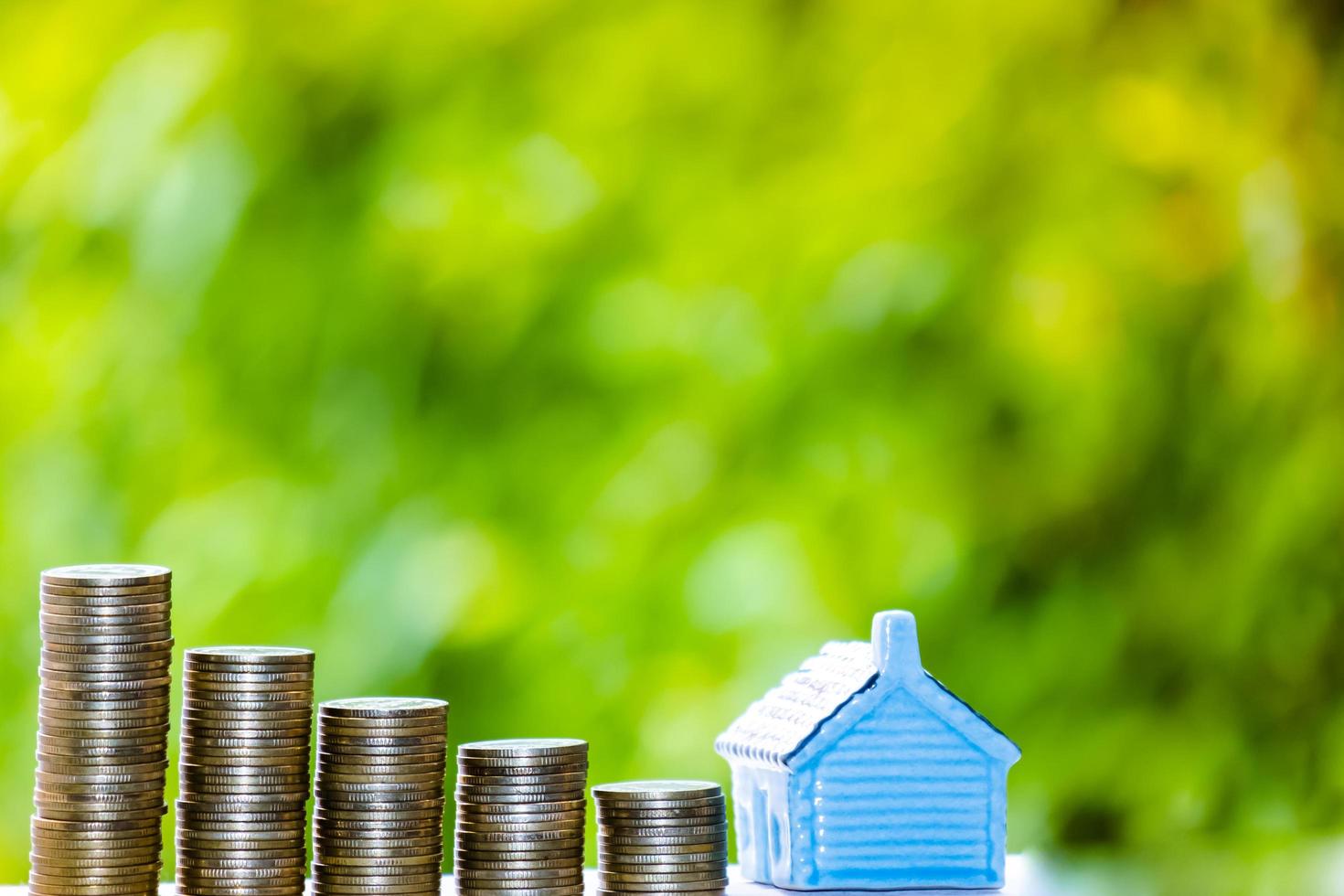 House model and coins money, Business Finance coin stack growing graph with green tree bokeh background,investment, loans and real estate concept photo