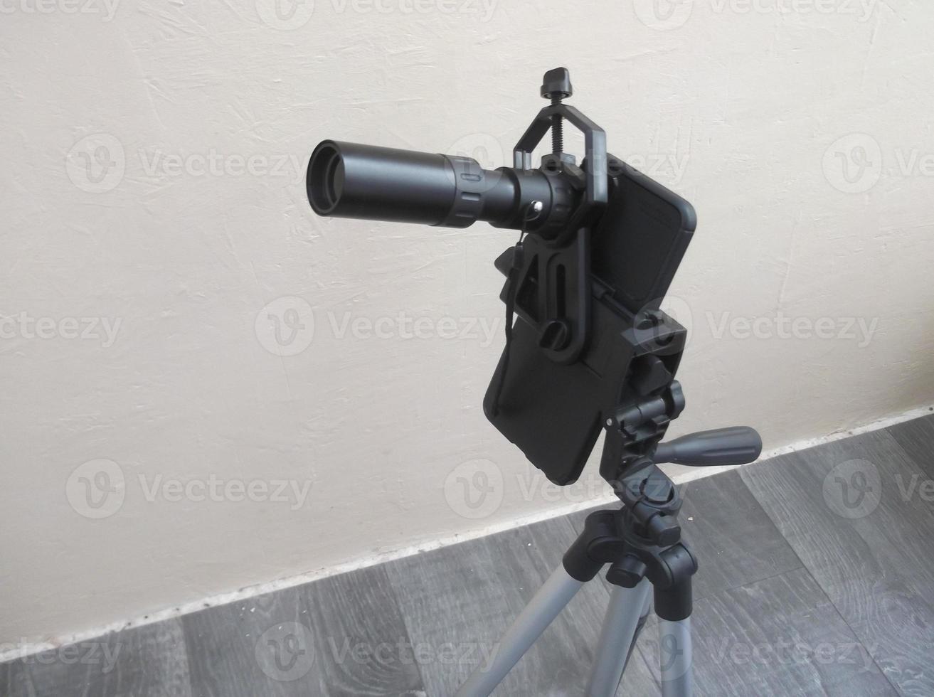 Attachment between monocular telescope and smartphone on a tripod photo