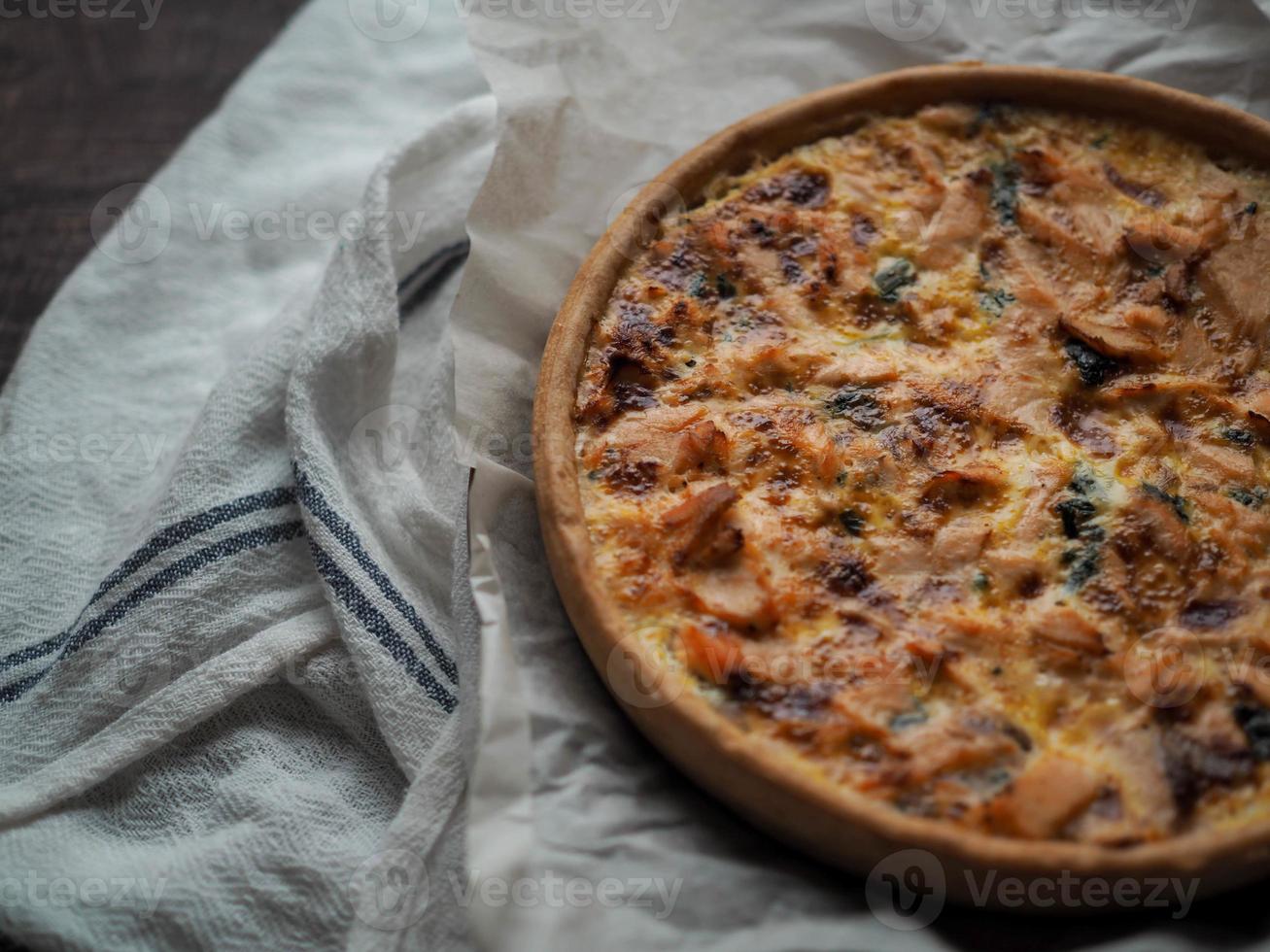 Home made salmon Quiche on a wood table with beautiful light for background photo