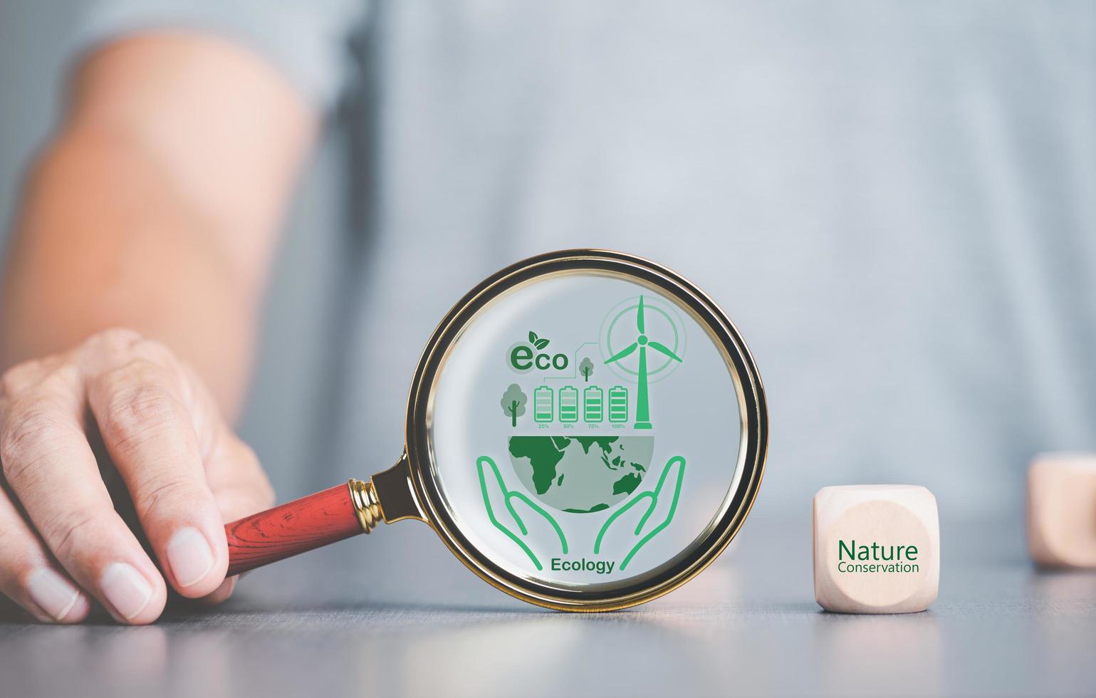 environmental conservation concept, protecting and preserving resources,planting trees to reduce global warming, using renewable energy, preserving natural forests,magnifying glass is placed on table photo