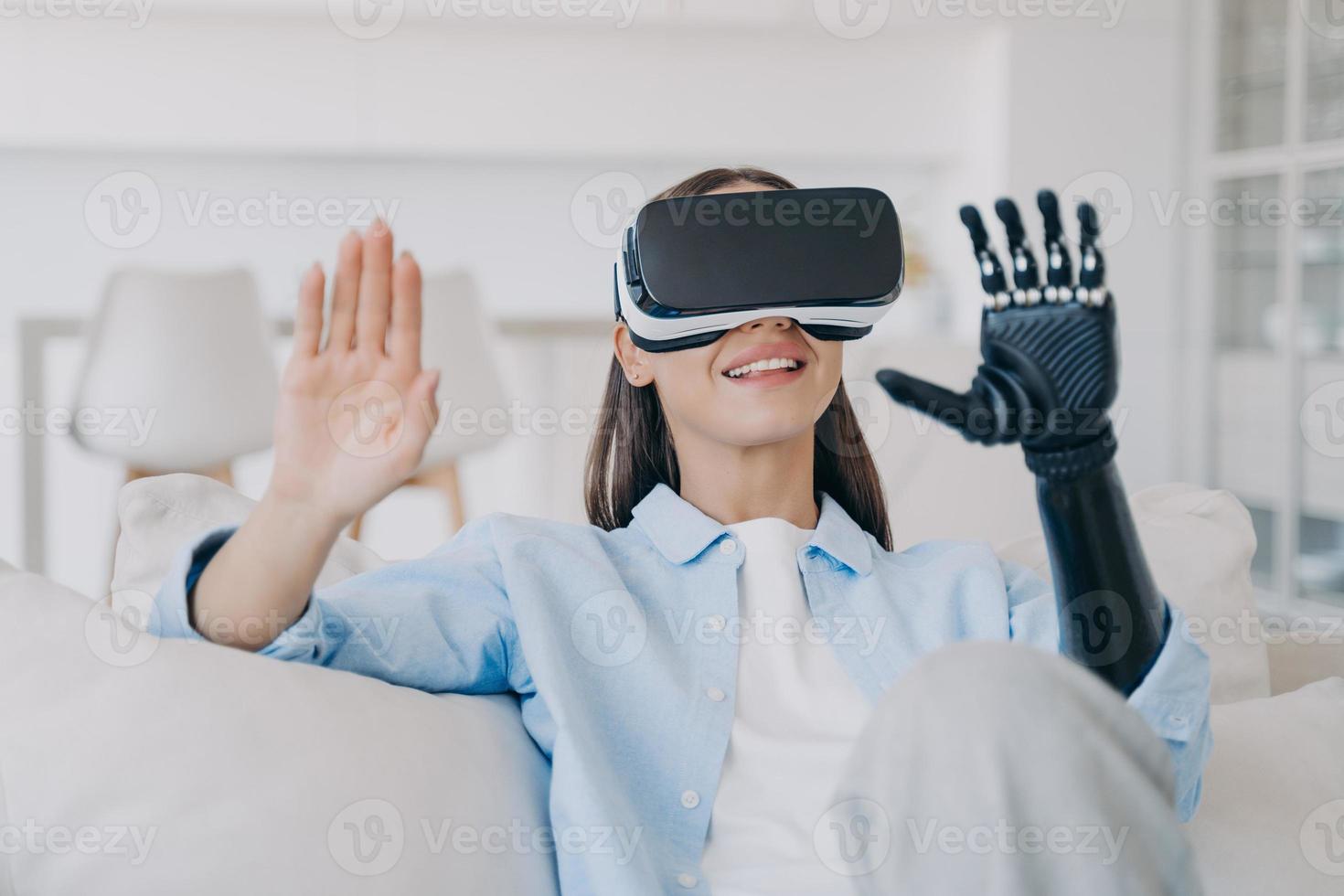 Smiling young girl wearing virtual reality glasses learning to use high tech bionic prosthetic arm photo