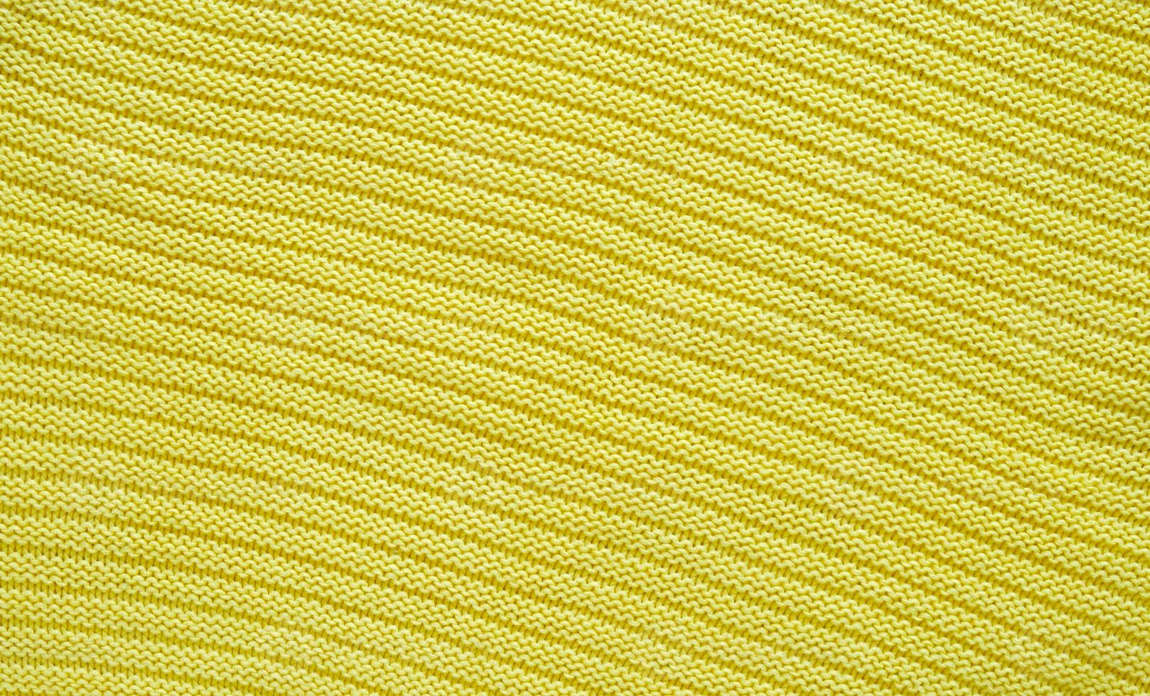 Texture of smooth knitted yellow sweater with pattern. Top view, close-up. Handmade knitting wool or cotton fabric texture. Background of knitting patterns. photo
