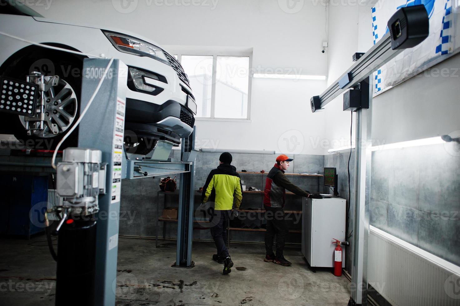 Auto mechanic sets american SUV car for diagnostics and configuration camber check in workshop of service station.. photo