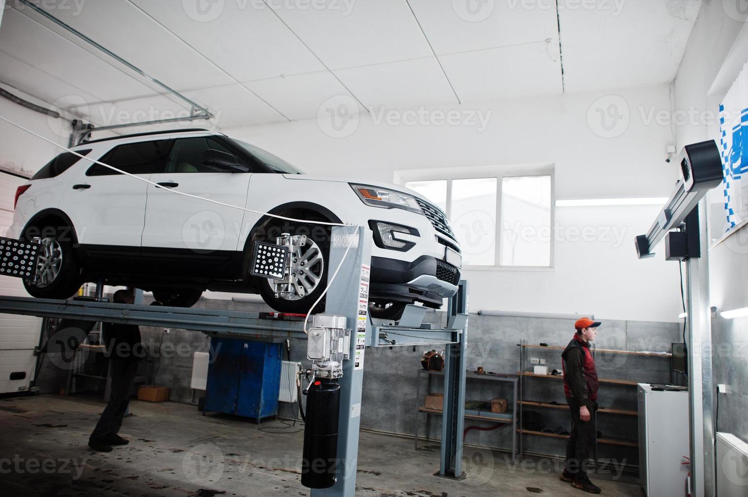 American SUV car on stand for wheels alignment camber check in workshop of service station. photo
