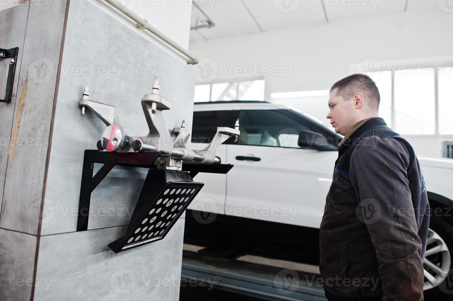 Auto mechanic sets american SUV car for diagnostics and configuration camber check in workshop of service station.. photo