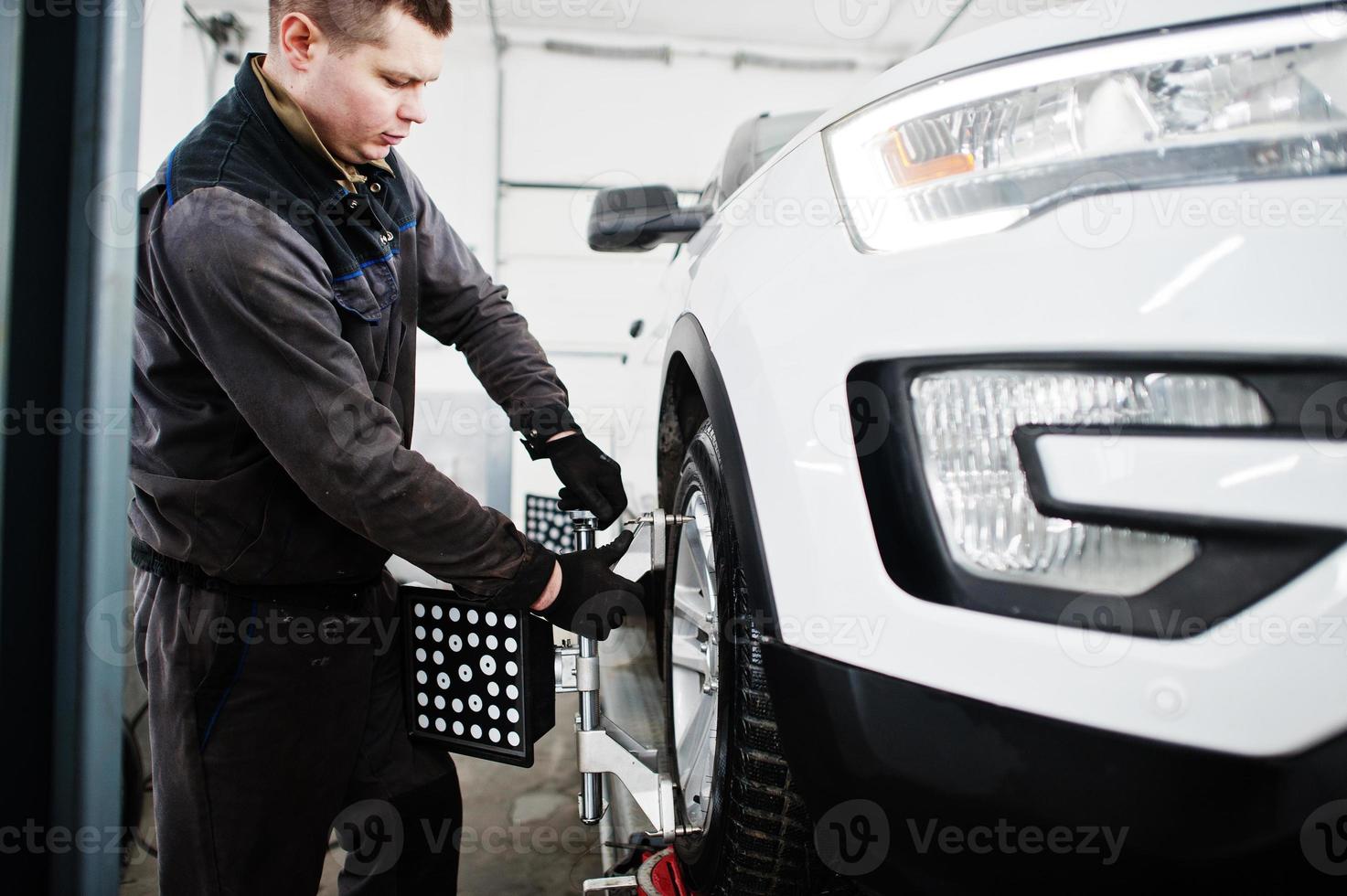 Auto mechanic sets american SUV car for diagnostics and configuration camber check in workshop of service station.. photo