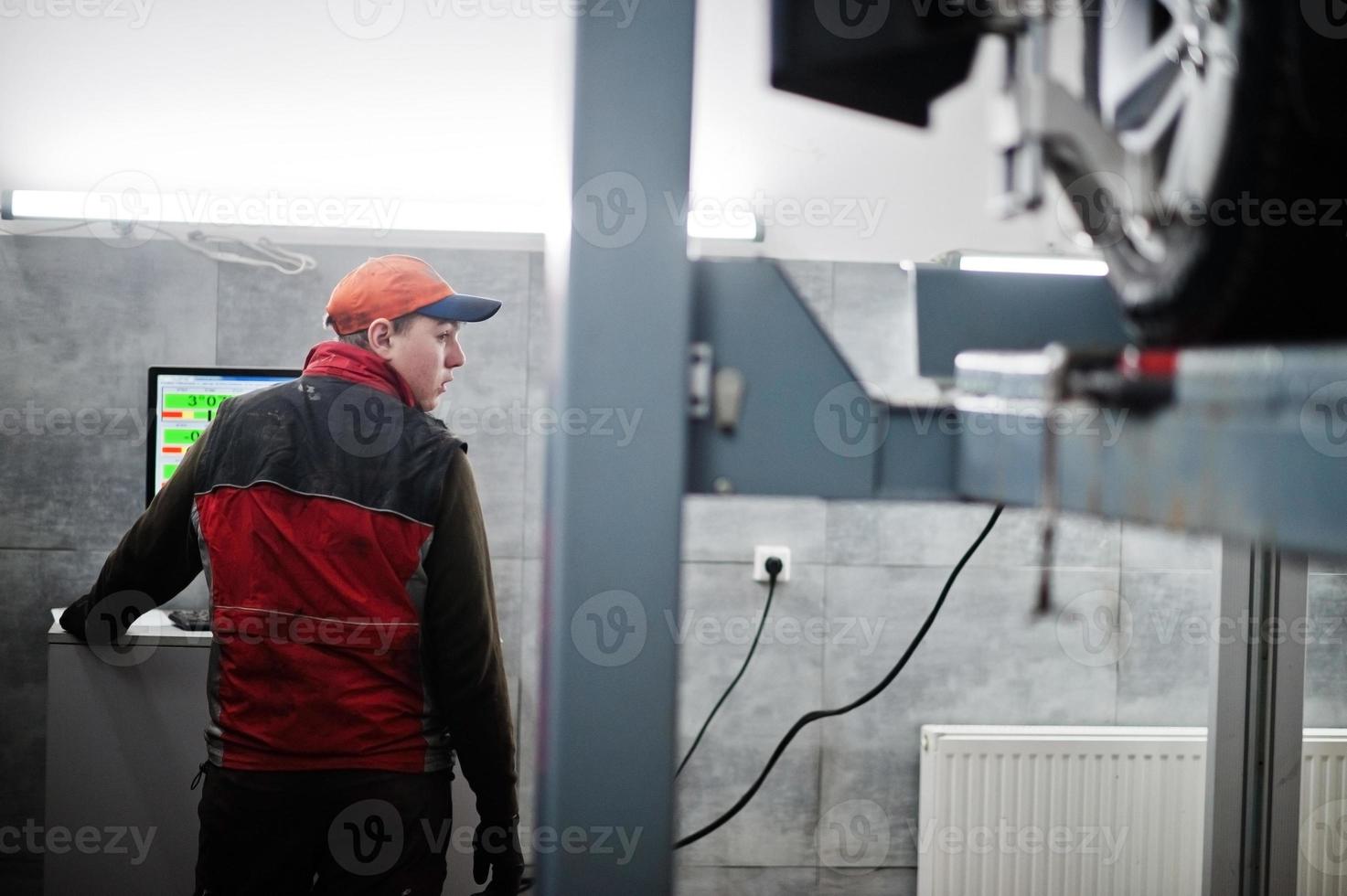 Auto mechanic sets american SUV car for diagnostics and configuration camber check in workshop of service station.. photo