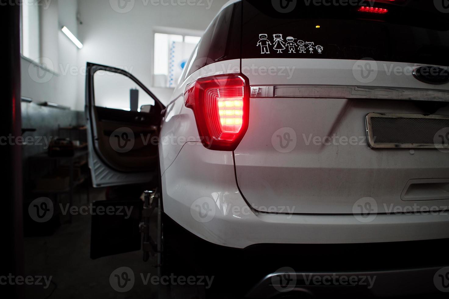 American SUV car on stand for wheels alignment camber check in workshop of service station. photo