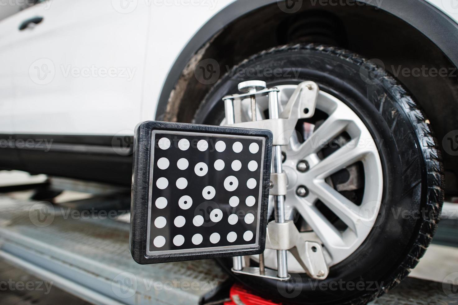 American SUV car on stand for wheels alignment camber check in workshop of service station. photo