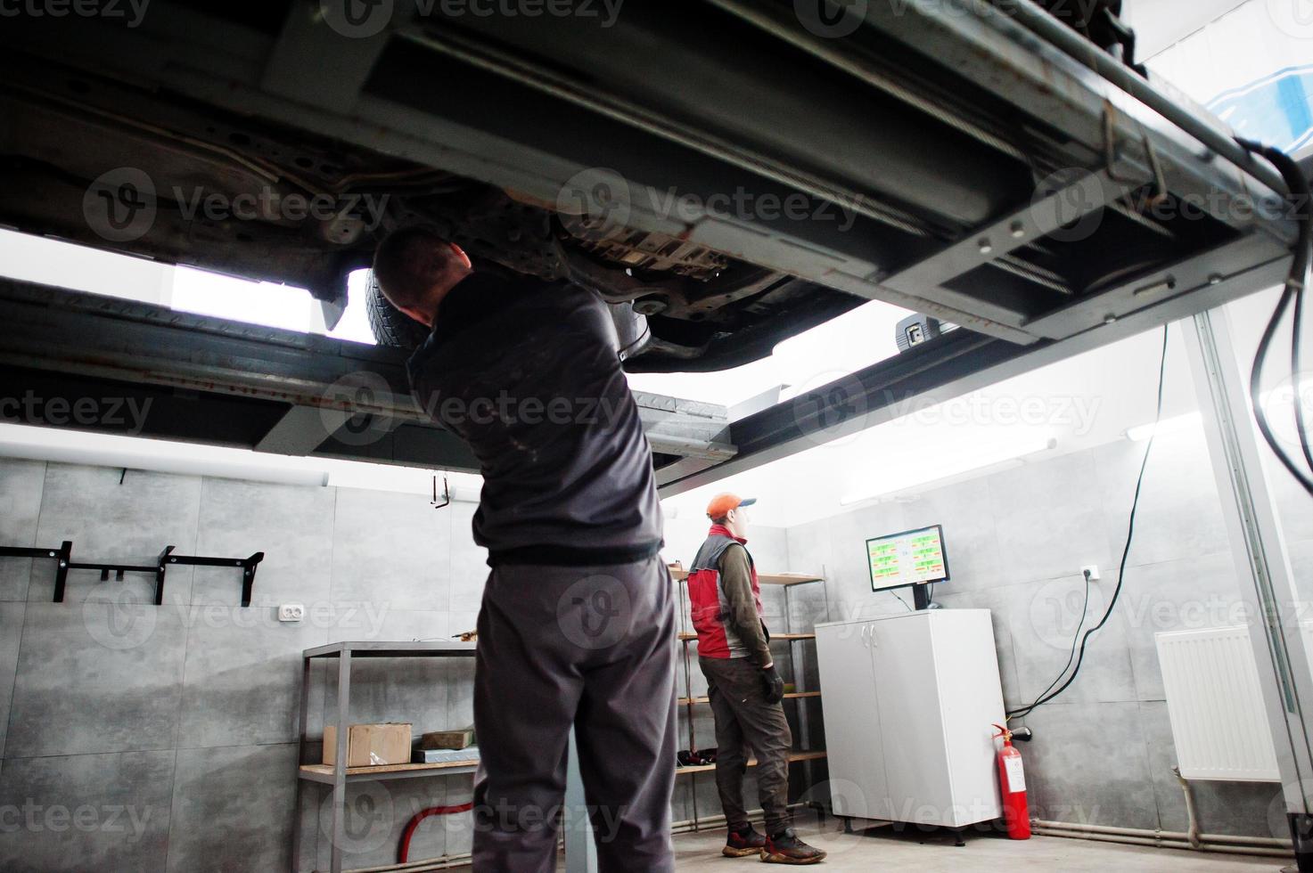 Auto mechanic sets american SUV car for diagnostics and configuration camber check in workshop of service station.. photo