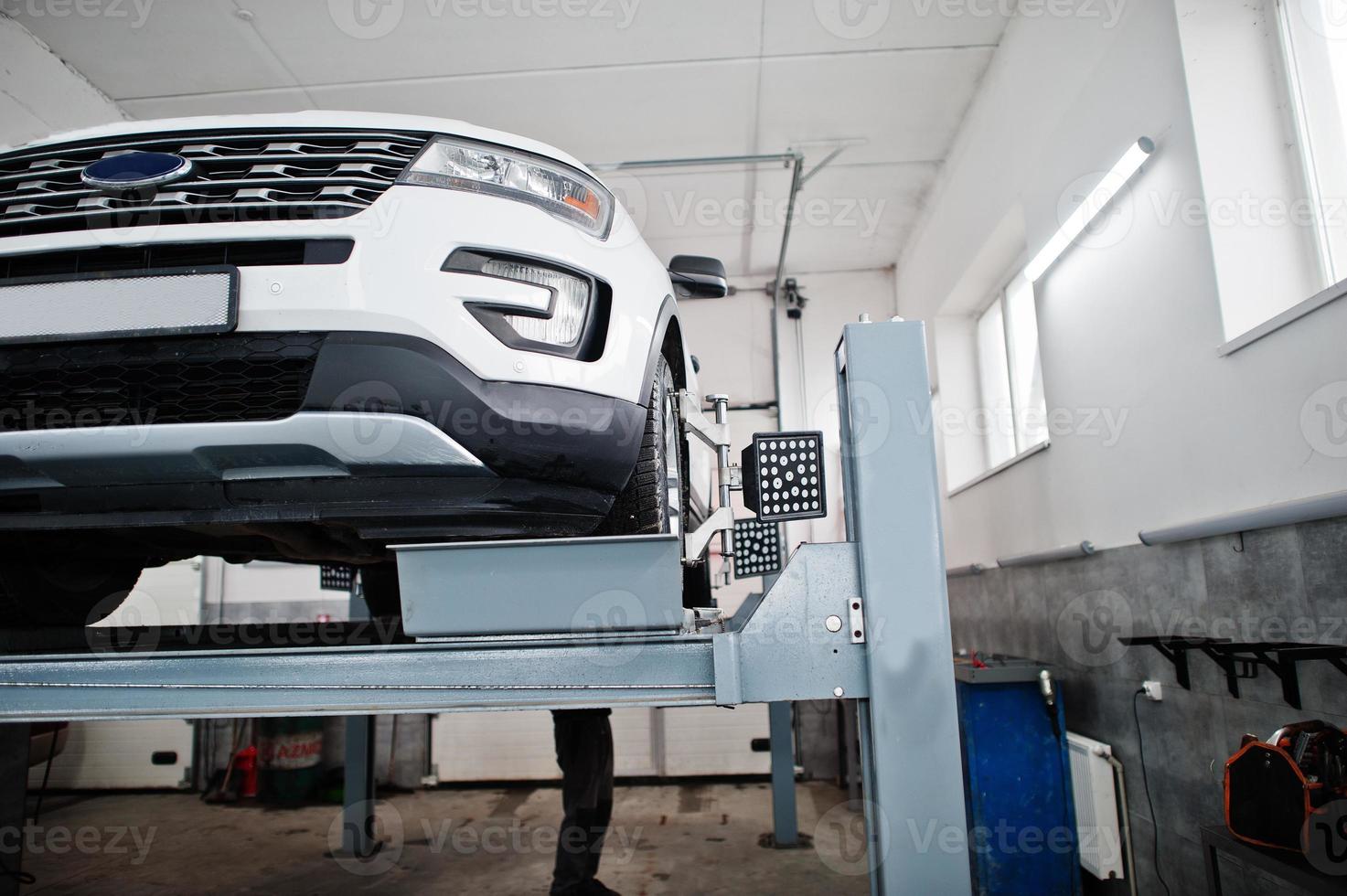 American SUV car on stand for wheels alignment camber check in workshop of service station. photo